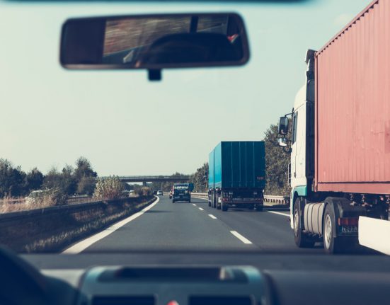 Car driving beside trucks