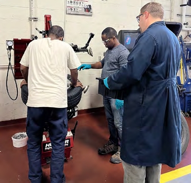 Participants Gutu Waqo and Wasiu Abdul learning how to fix a tire from instructor Adam LaPierre