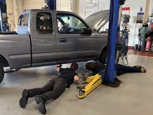 Participants Kaden Wright and Connor MacMullin laying on the floor determining where to securely hoist the truck